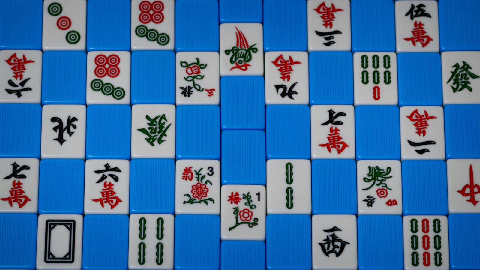 Detailed view of colorful Mahjong tiles arranged on a blue background, showcasing traditional symbols.